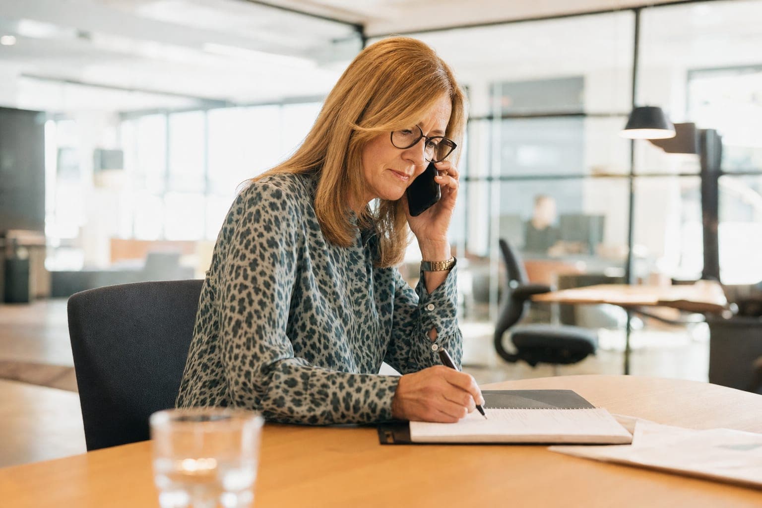 Recruiterin im Telefonat mit Notizblock am Schreibtisch